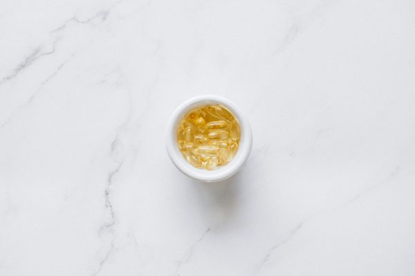 A bowl of transparent capsules on a marble background, offering ample copyspace.