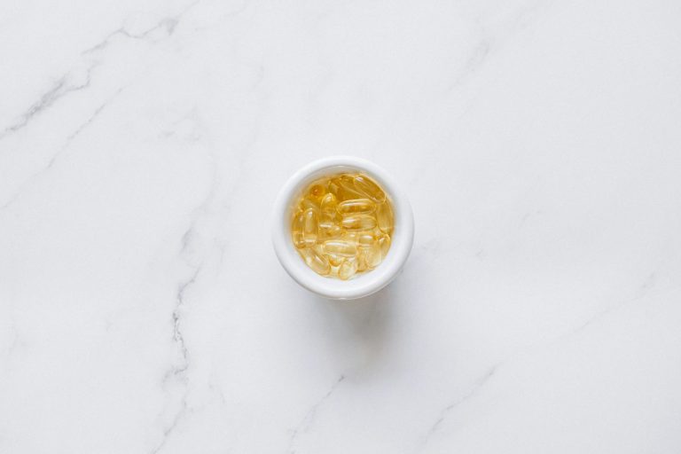 A bowl of transparent capsules on a marble background, offering ample copyspace.