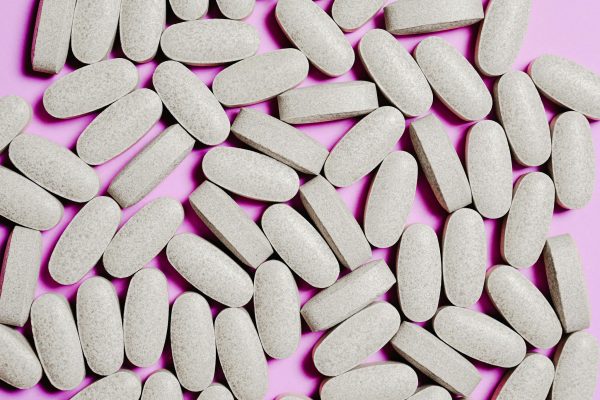 A close-up view of oval tablets scattered on a purple surface. Ideal for healthcare and pharmaceutical concepts.