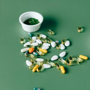 Assorted pills and herbal remedies displayed on green surface, emphasizing natural health concepts.