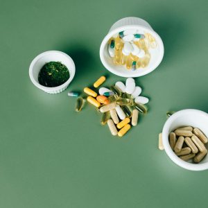 Various herbal and vitamin pills and capsules on a green surface.